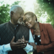 An elderly couple smiles and leans into each other.