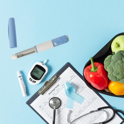 Black heart-shaped bowl full of colorful veggies, next to a stethoscope, clipboard, blue ribbon, glucose monitor, and syringe.