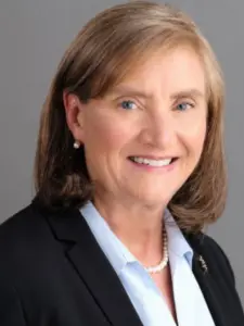 Woman with brown bob in black suit jacket smiles in professional headshot